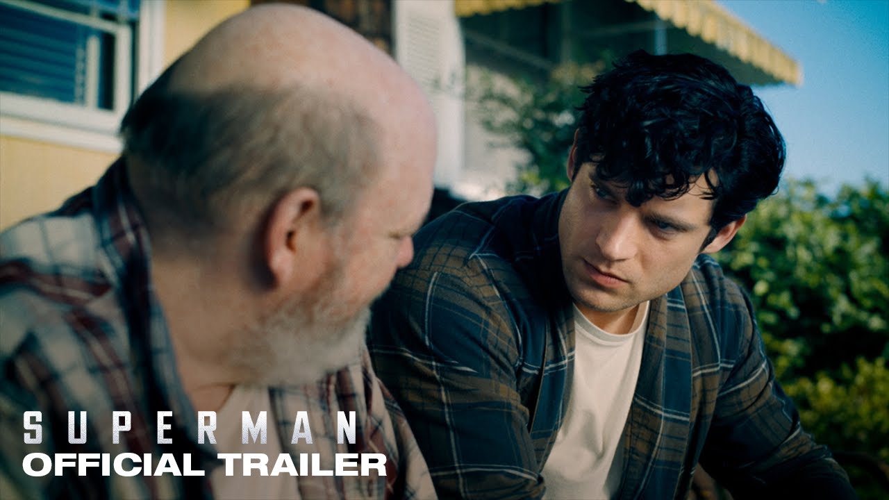 Young Clark Kent sits in a heartfelt conversation with an older man on a sunny porch — a still from Superman 2025 official trailer